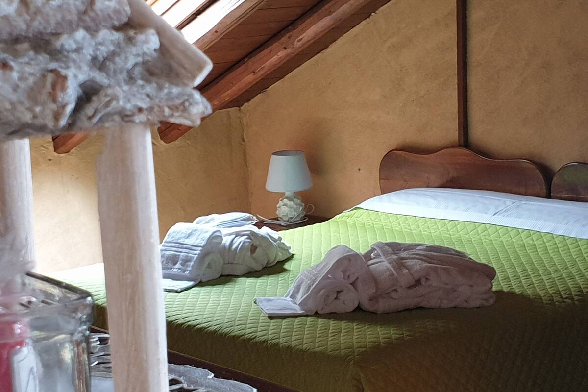 Een kamer met een bed, een nachtkastje met een lamp en een raam.