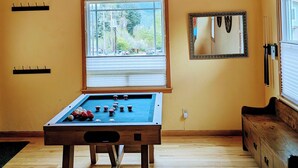 A room with a pool table, a window with a crescent moon decoration, and a mirror on the wall.
