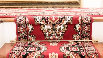 A room with a patterned red carpet and a wooden bench.
