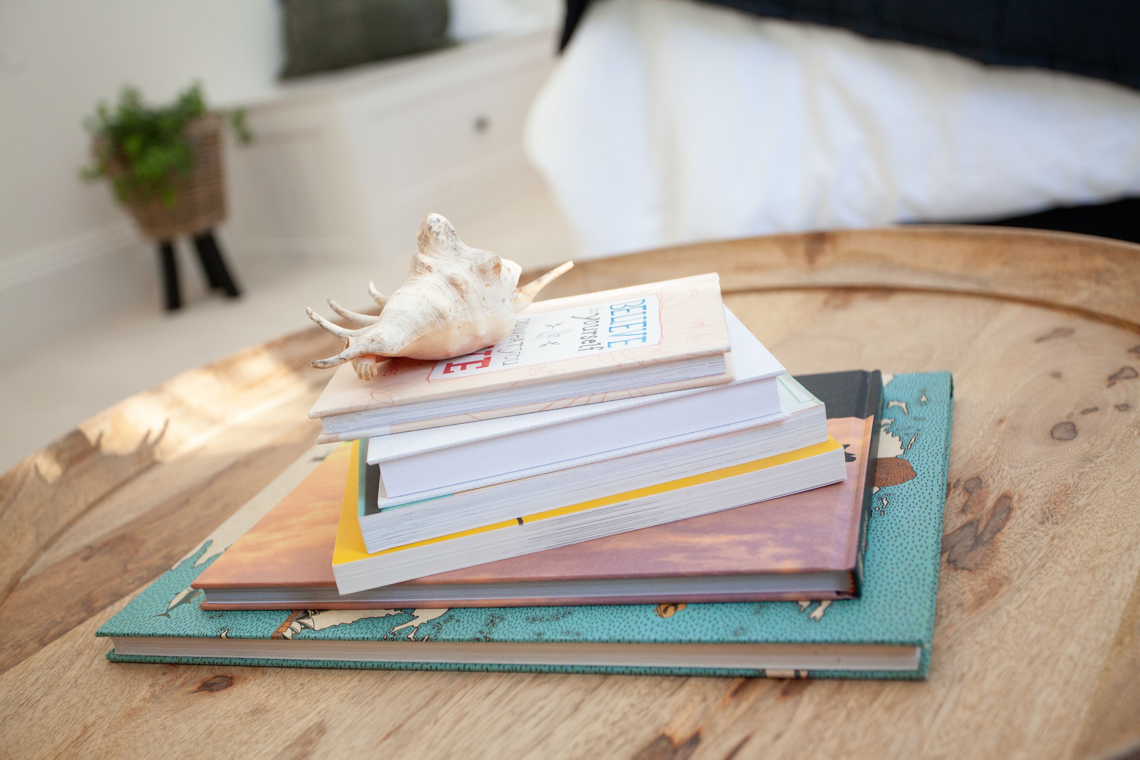 Een stapel boeken op een houten tafel, met een schelp bovenop.