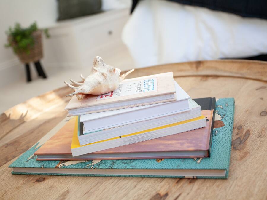 Een stapel boeken op een houten tafel, met een schelp bovenop.