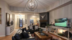 Un salón amplio con chimenea, sofás de cuero, una mesa de centro y un televisor.