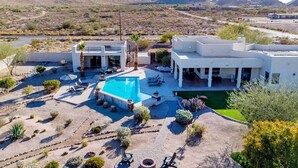 Una casa moderna con piscina, mobiliario de patio y vista a las montañas.
