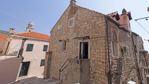 Un edificio de piedra con tejado rojo, una torre de campanas y una puerta pequeña.