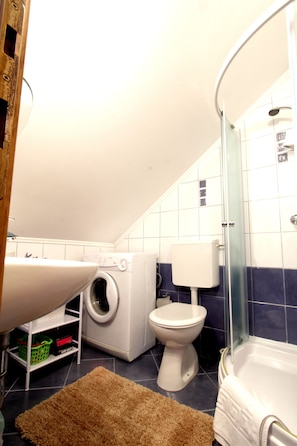 A bathroom with a washing machine, toilet, and bathtub.