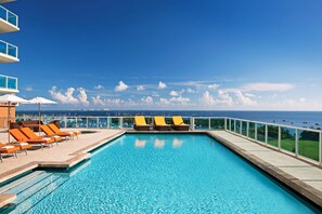 A swimming pool with lounge chairs and a view of the ocean. - Panoramic Bay View Studio | Grove Getaway (Miami)