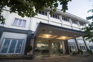 A multi-story building with large windows and a covered entrance area. - OYO 1401 Hotel Maya (Kupang)