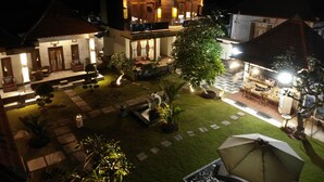 A well-lit courtyard with a dining area, a pool, and a large tree. - Gus Mank Stay (Penida Island)
