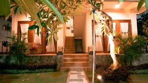 A house with a staircase leading to a wooden door, surrounded by lush greenery and a well-maintained lawn. - Gus Mank Stay (Penida Island)