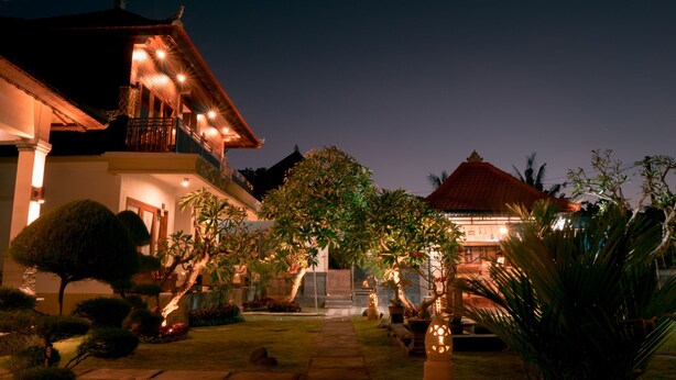 A two-story house with a balcony, surrounded by well-maintained gardens and a pathway leading to the entrance. - Gus Mank Stay (Penida Island)