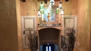 Een gang met een openhaard, twee deuren en decoratieve verlichting.