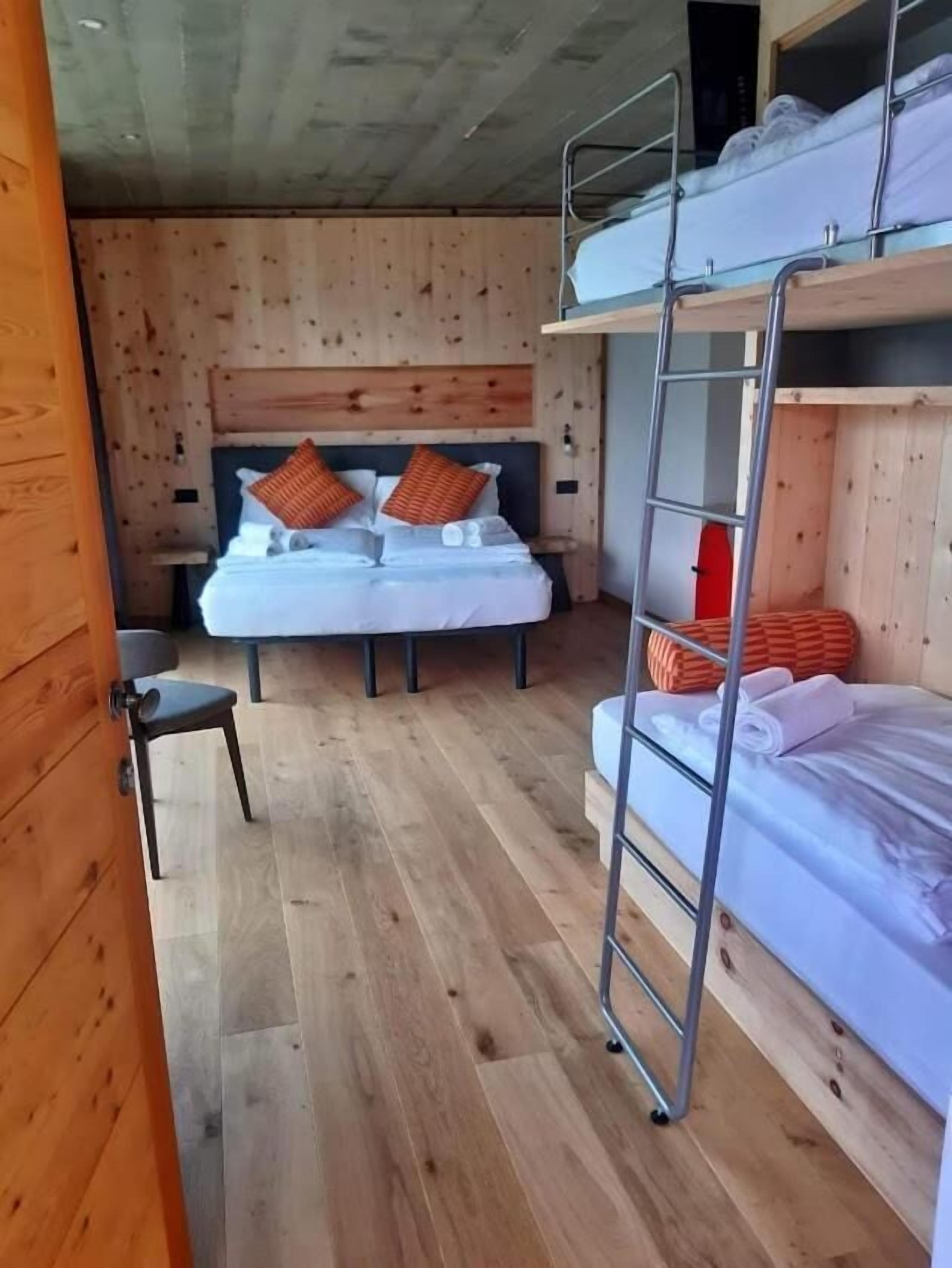 A compact room with two bunk beds, a small chair, and a ladder.
