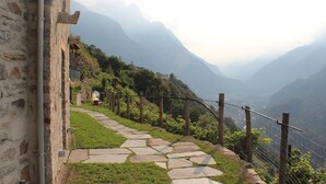 A stone pathway leading uphill with a rustic fence and a building on the left.