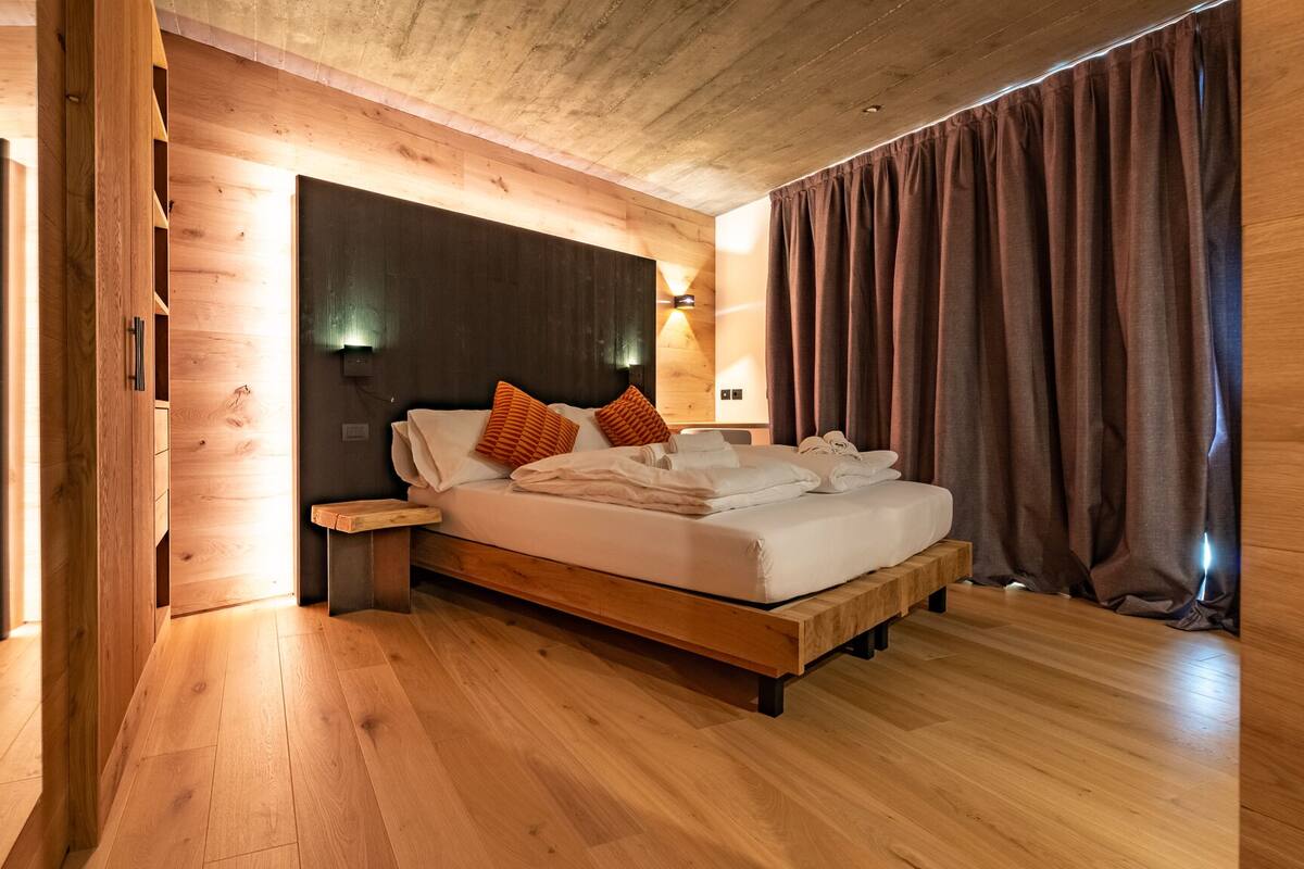 A wooden room with a bed, nightstands, and a bench.