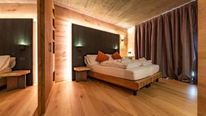 Ein Zimmer mit Holzboden, einem Bett, Nachttischen und einer Bank.