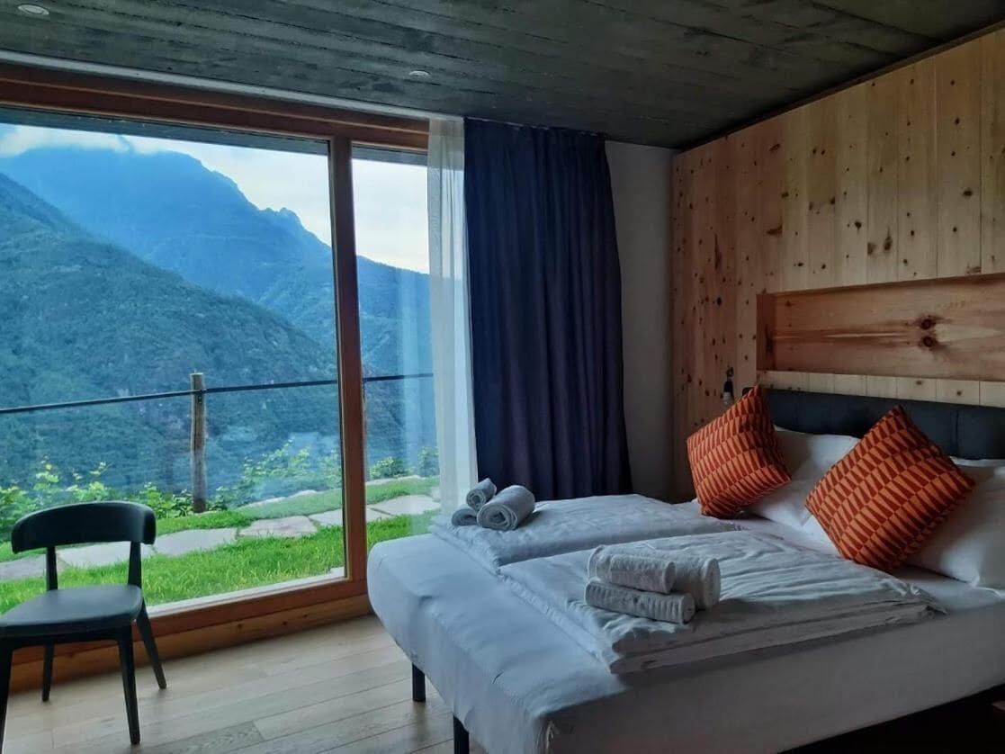 Un dormitorio con un ventanal grande, cabecera de madera y dos camas con toallas.