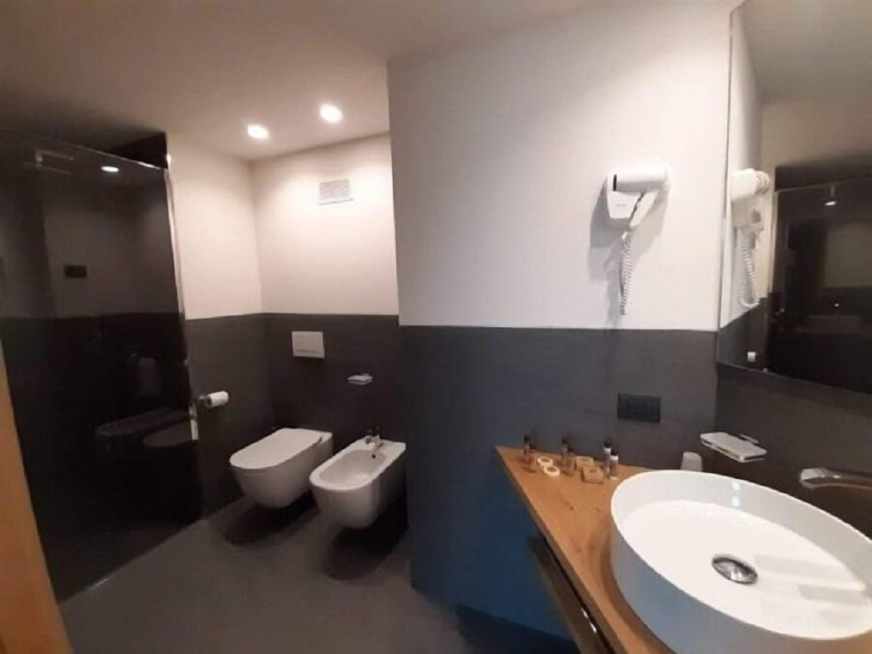 A modern bathroom with a bidet, a toilet, a large sink, and a mirror.