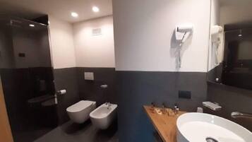 Un bagno moderno con bidet, servizi igienici, un lavandino capiente e uno specchio.