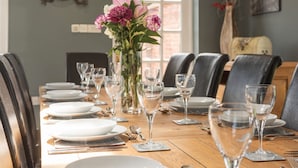 Une table à manger dressée avec des assiettes, des verres et des couverts, entourée de chaises.