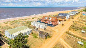 A coastal residential area with houses, a beach, and a clear sky.