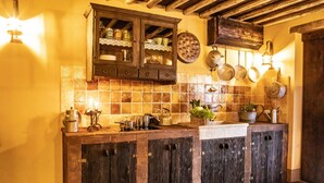 Una cocina rústica con armarios de madera, salpicadero de azulejos y diversos utensilios de cocina.