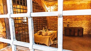 Un comedor rústico con una mesa dispuesta para dos personas, que incluye una botella, vasos y pan.