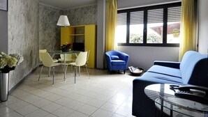 A compact living space with a dining area, a sofa, and a window with curtains.