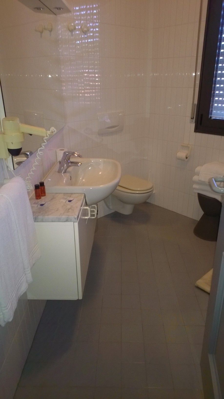 Un baño con lavamanos, inodoro y espejo.
