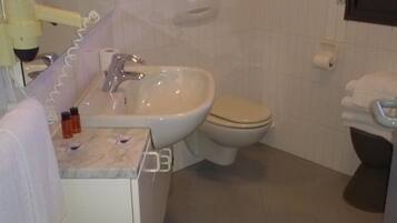 Un baño con lavamanos, inodoro y espejo.