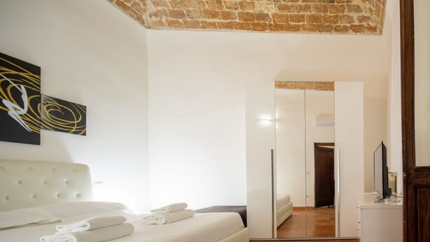 A bedroom with a bed, a mirror, and a television. - An apartment for rent with Santa Croce view by Mmega (Firenze)