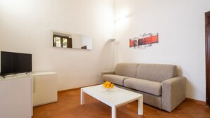A living room with a white coffee table, a beige sofa, a flat-screen TV, a white cabinet, and a wall-mounted artwork. - An apartment for rent with Santa Croce view by Mmega (Firenze)