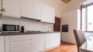 A modern kitchen with white cabinetry, a microwave, a red coffee machine, and a dishwasher. - An apartment for rent with Santa Croce view by Mmega (Firenze)