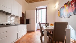 A modern kitchen with white cabinets, a dining area with a table and chairs, and a brick ceiling. - An apartment for rent with Santa Croce view by Mmega (Firenze)