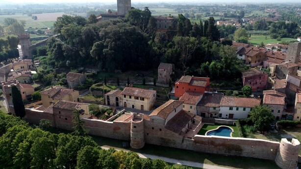 Una città fortificata con edifici storici, una torre e un fossato.