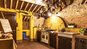 Una cucina rustica con pareti in mattoni a vista, travi in legno e pentole appese.