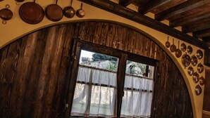 Una stanza rustica con un'ampia finestra ad arco, travi in legno e una collezione di pentole appese.