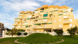 Un immeuble résidentiel à plusieurs étages, doté de balcons, d’une cour intérieure et d’une clôture périphérique.