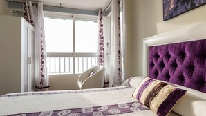 Une chambre à coucher avec un lit, une chaise et un balcon avec des rideaux.