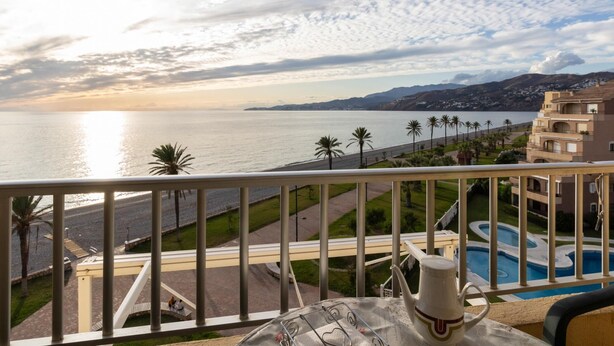 Un balcon avec vue sur la mer, une piscine et un immeuble doté de balcons.