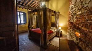A rustic bedroom with a four-poster bed, stone walls, and a wooden ceiling. - Apt. LA TORRE - "Manor of Brunelleschi" Medieval Apartments Resort (Vicopisano)