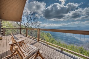 A wooden deck with a covered seating area overlooking a mountainous landscape.