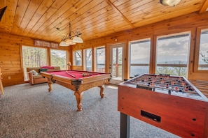 Un intérieur en bois avec une table de billard, un baby-foot et un canapé.