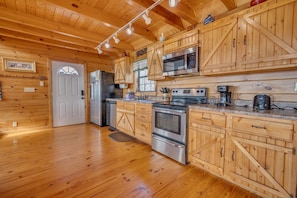 L’intérieur d’un chalet en bois comprend une cuisine équipée d’un réfrigérateur, d’un four à micro-ondes, d’une cuisinière et d’un four, le tout en acier inoxydable.