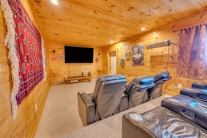 Interior em madeira com televisão de tela plana, poltronas de massagem e um painel de parede estampado.