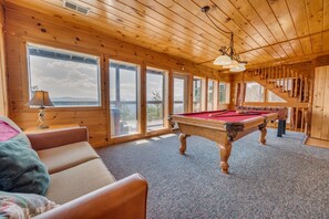 Un intérieur en bois avec une table de billard, un canapé et un escalier.