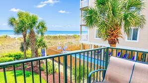 Un balcón con vista a la playa, una piscina y una silla.