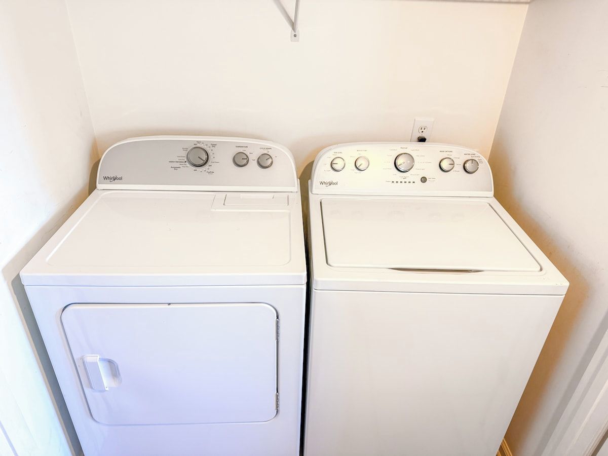 Two white Whirlpool front-loading washing machines in a laundry room.