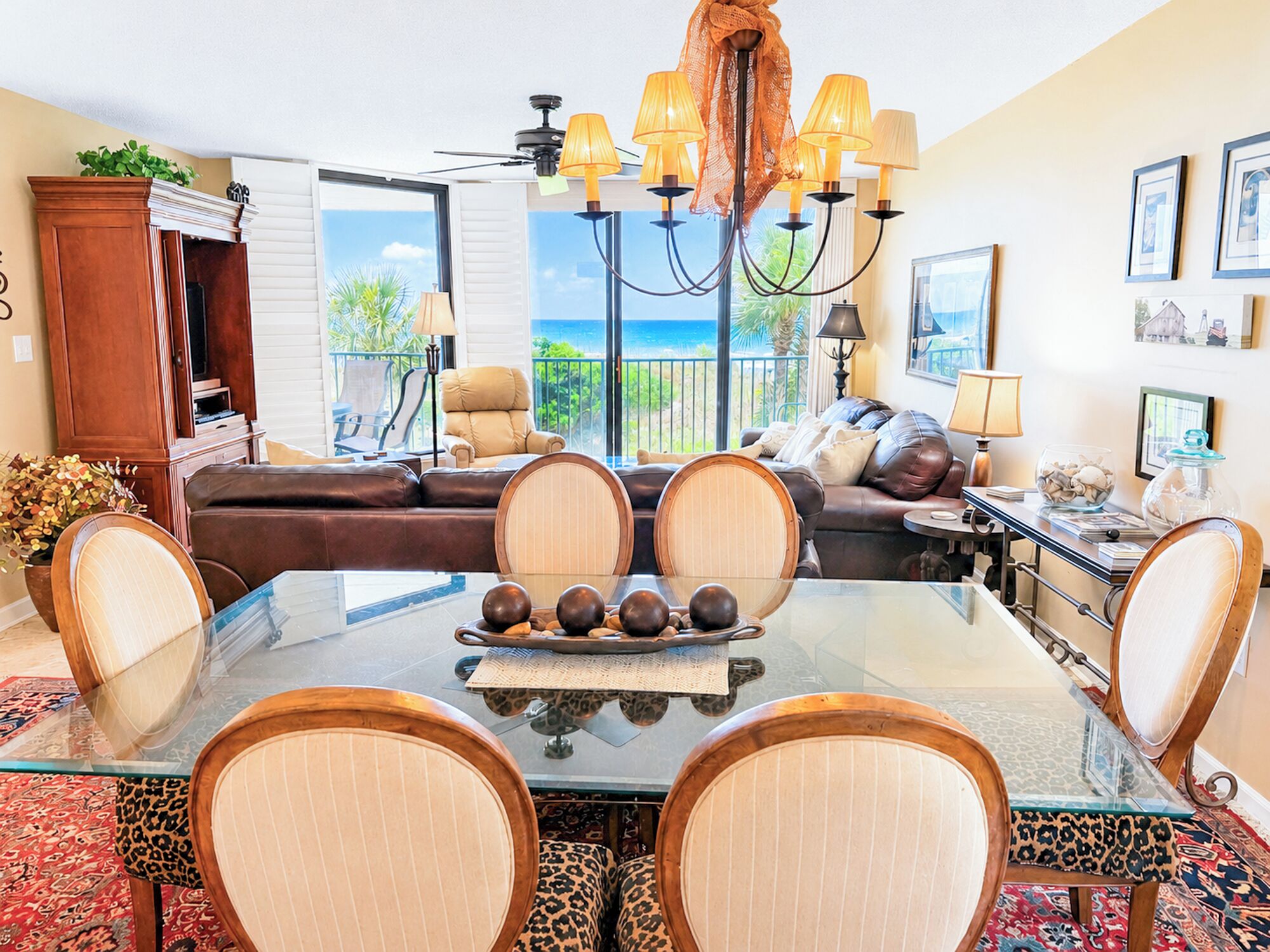 A dining area with a glass table, chairs, and a chandelier.