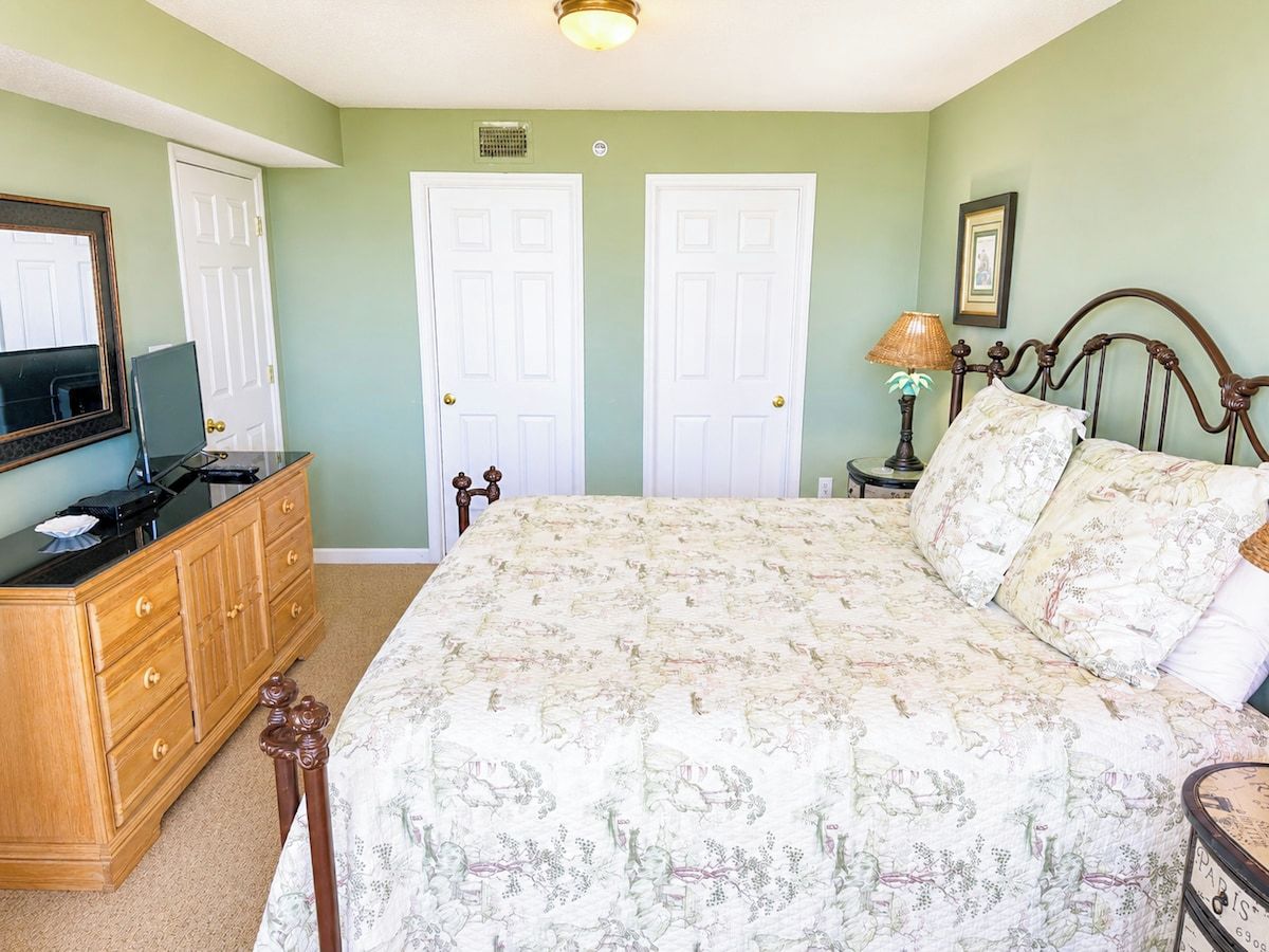 Un dormitorio con cama, cómoda y lámpara.