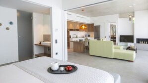 A modern hotel room with a bed, a dining area, and a living space. - Villa Fyki (Lefkada)